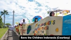 Aksi pembentangan spanduk sepanjang 220 meter di pelataran Monas, Jakarta, suarakan pentingnya aksi nyata atasi ancaman krisis iklim dan kemiskinan pada anak, Sabtu (29/10). (Foto: Save the Children Indonesia).