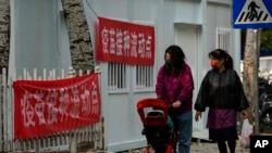 资料照：带着口罩推着婴儿车的女子走过北京的一处疫苗接种流动点。（2022年10月26日）