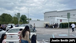 Para pengunjung berjalan melintasi lapangan parkir di Mal Columbiana Centre di Columbia, South Carolina, Sabtu, 16 April 2022 saat polisi menyelidiki penembakan di pusat perbelanjaan itu. (Foto: Justin Smith via AP)