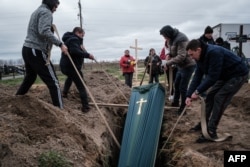 Relatives of Mykhailo Romaniuk, 58, who was shot dead on his bicycle on March 6, help to bury his coffin at a cemetery in Bucha, on April 19, 2022, during the Russian invasion of Ukraine.