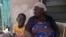 Funmilayo Kotun, a malaria patient, sits with her grandson Ayomide Kotun outside her house in Lagos, Nigeria, on April 20, 2024.