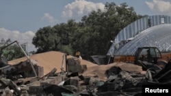 Seorang karyawan mengemas jelai ke dalam tas tempat gudang biji-bijian dihancurkan oleh serangan rudal Rusia, di tengah serangan Rusia ke Ukraina, di kompleks perusahaan pertanian di desa Pavlivka, di wilayah Odesa, Ukraina 21 Juli 2023. (Foto: REUTERS/Nina Liashonok)