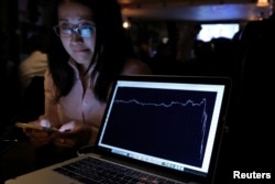FILE - A woman watching the Brexit vote in The Churchill Tavern, a British themed pub, reacts as a graph shows the British Pound falling in value following the announcement that Britain would leave the European Union.