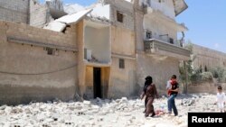 FILE - Civilians make their way on a street littered with the rubble of buildings damaged by air strikes in Aleppo, May 14, 2014.
