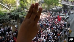 Myanmar nationals living in Thailand display the three-finger symbol of resistance during a protest marking the anniversary of the military takeover that ousted their government outside the Myanmar Embassy in Bangkok, Thailand, Feb. 1, 2023.