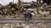 Men ride bicycles by a destroyed apartment building in Borodyanka, Ukraine, April 6, 2022.