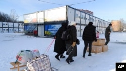 People carry their belongings at a modular town for refugees from war-hit Ukrainian regions in Lviv, Ukraine, Feb. 9, 2023.
