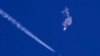 Sisa-sisa balon mata-mata China melayang di atas Samudera Atlantik, tak jauh dari pantai Carolina Selatan, dengan sebuah jet tempur dan jejaknya terlihat di bawahnya, 4 Februari 2023. (Foto: via AP)