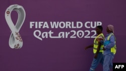 FILE - Workers walk past a FIFA World Cup sign in Doha on Nov. 16, 2022, ahead of the Qatar 2022 World Cup football tournament. 