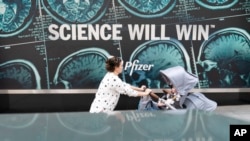 ARHIVA: Žena sa bebom prolazi pored sedišta farmaceutske kompanije Fajzer u Njujorku, 23. maja 2022. 