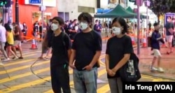 周嘉发（左一）与该党主席陈宝莹（右一）及成员余炜彬，6月4日晚在铜锣湾进行默站快闪悼念六四行动。 （社民连社交网站图片）