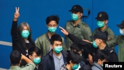 FILE - Pro-democracy activist Leung Kwok-hung, also known as 'Long Hair,' gestures as he walks to a prison van with other activists to head to court over a national security law charge, in Hong Kong, March 4, 2021.