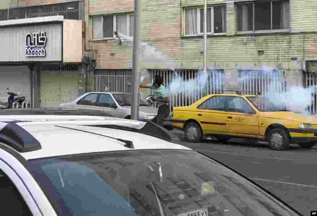 In thi Sept. 20, 2022, photo taken by an individual not employed by the Associated Press and obtained by the AP outside Iran, a protester throws a tear gas back at the anti-riot police during a protest over the death of a young woman held by morality police, in downtown Tehran.