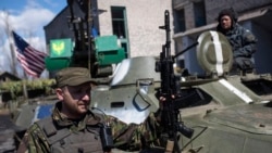 FILE - A Ukrainian serviceman stands near an armored vehicle, with a U.S. flag, in Shyrokyne, eastern Ukraine, April 15, 2015.
