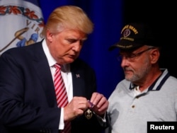 Republican U.S. presidential nominee Donald Trump talks to Lt. Col. Louis Dorfman, who gave Trump his Purple Heart, during a campaign event at Briar Woods High School in Ashburn, Virginia, Aug. 2, 2016.