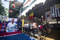 Para pemilih menunggu giliran memberikan suara dalam pilkada di sebuah TPS bertema Piala Dunia di Surabaya, 27 Juni 2018. (Foto: AFP)