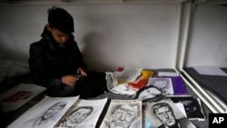 FILE - Farhad Nouri sits on a bed by portraits of Serbian tennis player Novak Djokovic, left, Spanish painter Salvador Dali, and German Chancellor Angela Merkel, third from left on March 13, 2017. (AP Photo/Darko Vojinovic)