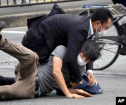 Tetsuya Yamagami, bottom, is detained near the site of gunshots in Nara Prefecture, western Japan, July 8, 2022. (Katsuhiko Hirano/The Yomiuri Shimbun via AP)