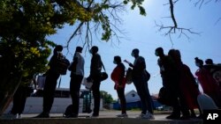 FILE - Migrants stand in line at a respite center after they crossed the U.S.-Mexico border and turned themselves in and were released, in Del Rio, Texas, June 16, 2021. 