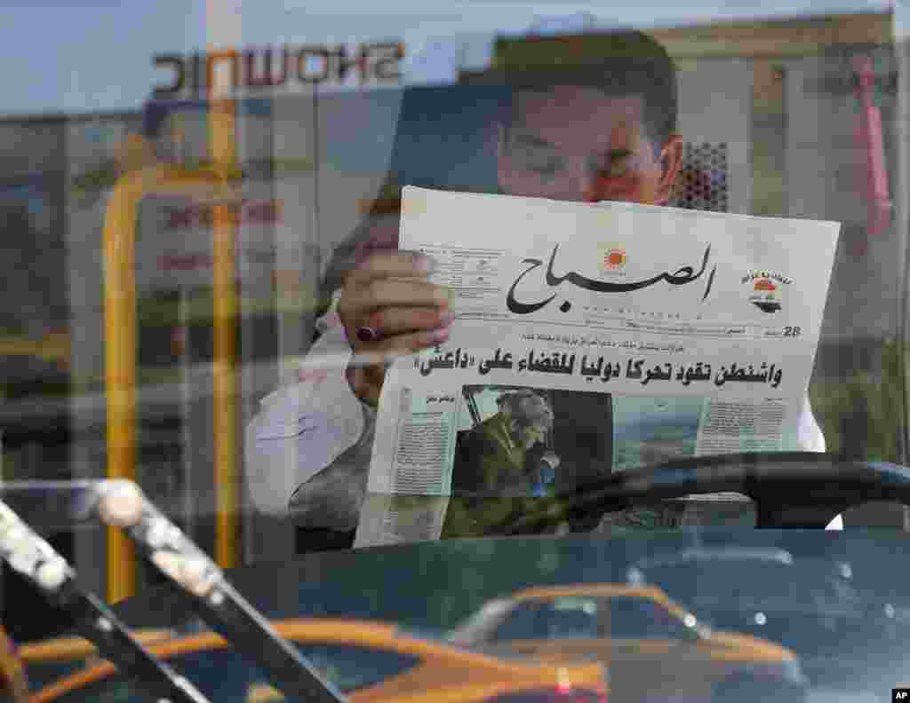An Iraqi man reads a newspaper with front page headlines reporting U.S. President Barack Obama's plan to battle Islamic State militants, with an accompanying photo of Secretary of State John Kerry's visit, in Baghdad, Sept. 11, 2014.
