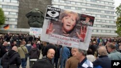Demonstrant drži poster sa prerađenom fotografijom Angele Merkel ispod koje piše "Angela mora da ode", u Kemicu, istočna Nemačka, 1. septembra 2018.