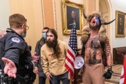 FILE - In this Jan. 6, 2021 file photo, supporters of Donald Trump, including Jacob Chansley, right with fur hat, are confronted by U.S. Capitol Police officers outside the Senate Chamber inside the Capitol in Washington.