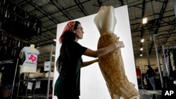 FILE - Samantha Estes prepares garments to be photographed at the ThredUp sorting facility in Phoenix, March 12, 2019. J.C. Penney and Macy’s are in the midst of rolling out a few dozen ThredUp branded shops each in time for the back-to-school season. 