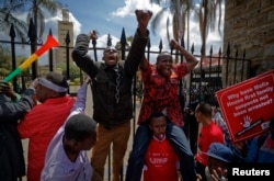 Protesters briefly climb the gates of Parliament, one holding a placard referring to President Uhuru Kenyatta, during an anti-corruption demonstration in Nairobi, Kenya, May 31, 2018.