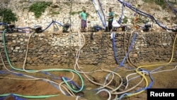 Villagers use pumps to get water from a partially dried-up pond as drought hits Penglai, Shandong province, China, July 8, 2015.