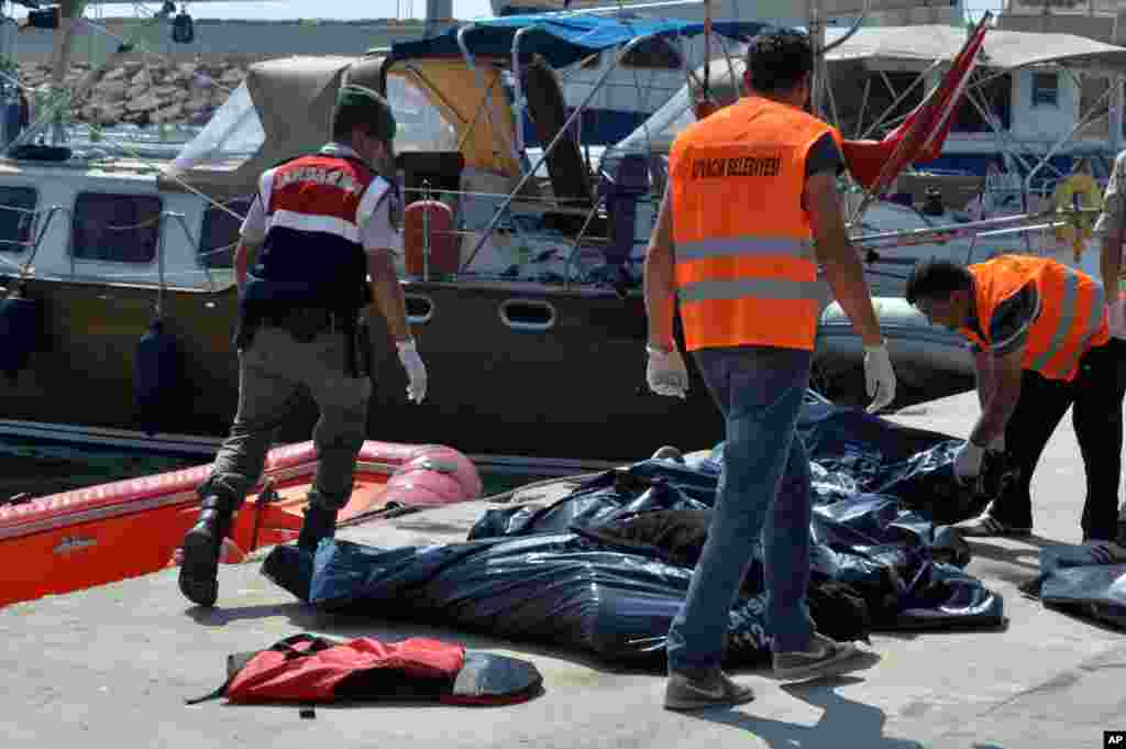 A Turkish paramilitary officer and local workers collect the bodies of migrants after their boat collided with a ferry off the Turkish coast near Ayvacik, Canakkale. Twenty six migrants were fear missing and search-and-rescue operations were ongoing, an official of Turkey's coast guard agency said.