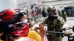 A federal officer pushes back demonstrators at the Mark O. Hatfield United States Courthouse in Portland, Ore., July 21, 2020.