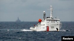 FILE - A Chinese Coast Guard vessel, with a disputed oil rig in the background, is seen in the South China Sea June 13, 2014.