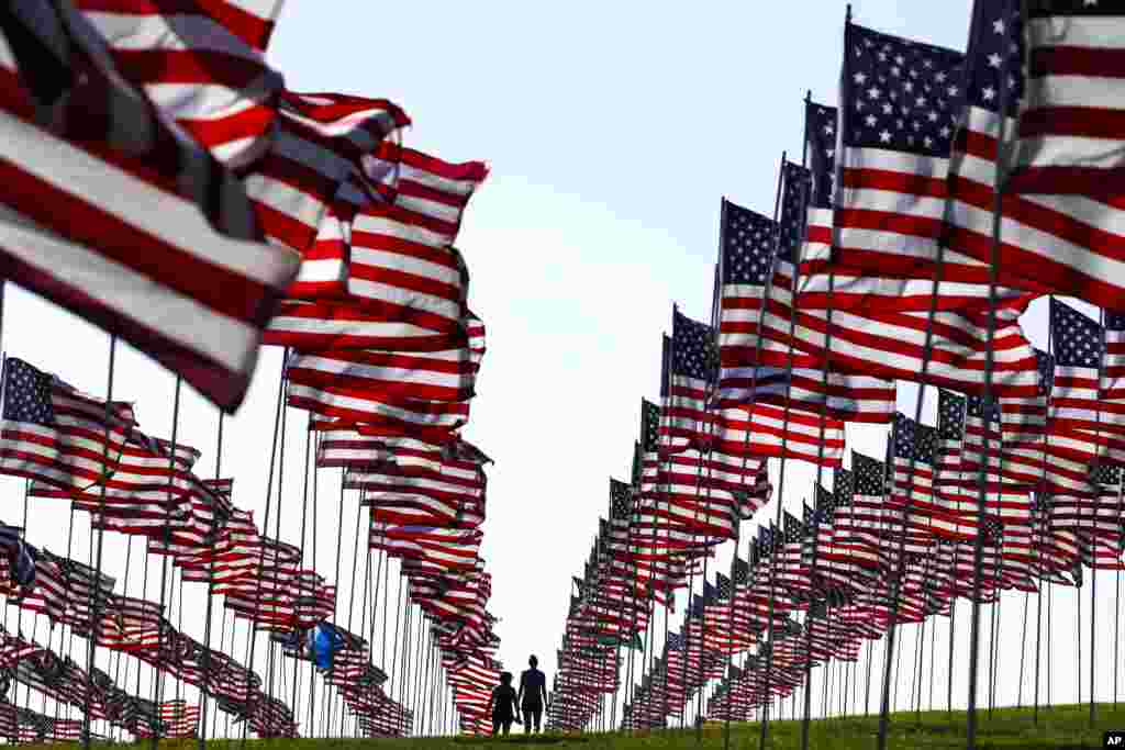 Bianca Burton, center left, and Erin Schultheis walk around the Pepperdine University's annual display of flags honoring the victims of the 9/11 terrorist attacks, Sept. 10, 2018, in Malibu, California.