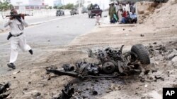 A Somali soldier runs to fight near the wreckage of a car bomb during an attack on Somalia's parliament, Saturday, May 24, 2014. 