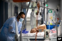 A medical staff member speaks with a COVID-19 patient in the infectious disease ward of the Strasbourg University Hospital, eastern France, Jan. 13, 2022. (AP Photo/Jean-Francois Badias)