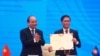Vietnamese Prime Minister Nguyen Xuan Phuc, left, applauds as Minister of Trade Tran Tuan Anh holds a signed document during a virtual signing ceremony of the Regional Comprehensive Economic Partnership trade deal in Hanoi, Vietnam, Nov. 15, 2020.
