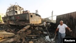 FILE - Workers inspect damage at the site of an air strike on the maintenance hub at the Hodeida port, Yemen, May 27, 2018. 