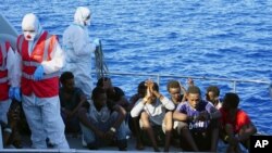 FILE - Migrants are evacuated by Italian Coast guards from the Open Arms Spanish humanitarian boat at the coasts of the Sicilian island of Lampedusa, southern Italy, Aug. 17, 2019. 