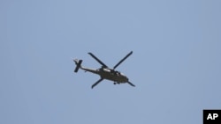 A U.S. military helicopter flies over the site of a suicide car bomb in Kabul, Afghanistan, Friday, May 31, 2019.