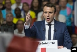FILE - Supporters of French presidential candidate Emmanuel Macron hold placards as he speaks during a campagin rally in Lyon, central France, Feb. 4, 2017.