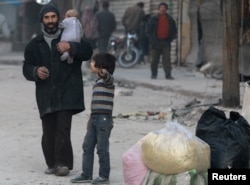 A boy gestures as he chats with his father in the rebel-held besieged al-Shaar neighborhood of Aleppo, Syria, Nov. 23, 2016.