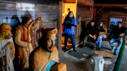 A medical worker and people waiting for COVID-19 vaccinations stand next to a nativity scene at the Christmas market in Offenbach, Germany, Nov. 24, 2021. The Christmas booth was turned into a temporary vaccination center, where people queued for hours.