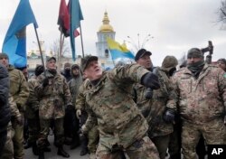 FILE - Mykola Kokhanivsky, commander of a volunteer battalion, throws a stone against the window of an office that belongs to Ukraine tycoon Rinat Akhmetov in Kyiv, Feb. 20, 2016.