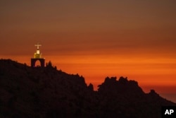 A cross sits on a cliff overlooking the sunset over the scenic Kadisha Valley, a holy site for Lebanon's Maronite Christians, in Bcharre, Lebanon, on July 21, 2023.
