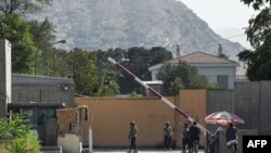 Afghan security personnel stand guard in front of a gate in the Green Zone in Kabul, Aug. 15, 2021.