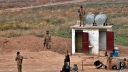 FILE - Fighters from the Syrian Democratic Forces stand guard at the Syrian side of the border with Iraq, Oct. 16, 2019.