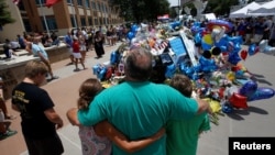People hug at at a makeshift memorial at police headquarters following the multiple police shootings in Dallas, Texas, U.S., July 10, 2016.