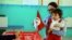 FILE - A woman casts her vote with her child during the first round of the Tunisian presidential election in a polling station at Marsa, outside Tunis, Nov. 23, 2014. The vote was another step forward in Tunisia's peaceful transition to democracy.