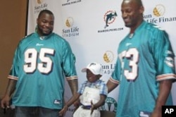 Miami Dolphins Jason Ferguson, left, and Reggie Torbor with Haiti earthquake survivor Snyder, 3 in Little Haiti, 7 Apr 2010