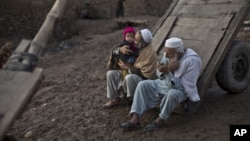 FILE - An elderly Afghan refugee trims his beard while another plays with his grandson on the outskirts of Islamabad, Pakistan. The Afghan government revealed Monday that more than one million refugees have “voluntarily” returned home from Pakistan and Iran in 2016.